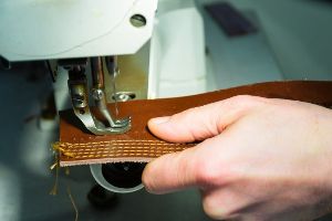 A person is sewing a leather strap on one of the best sewing machines for canvas and leather.